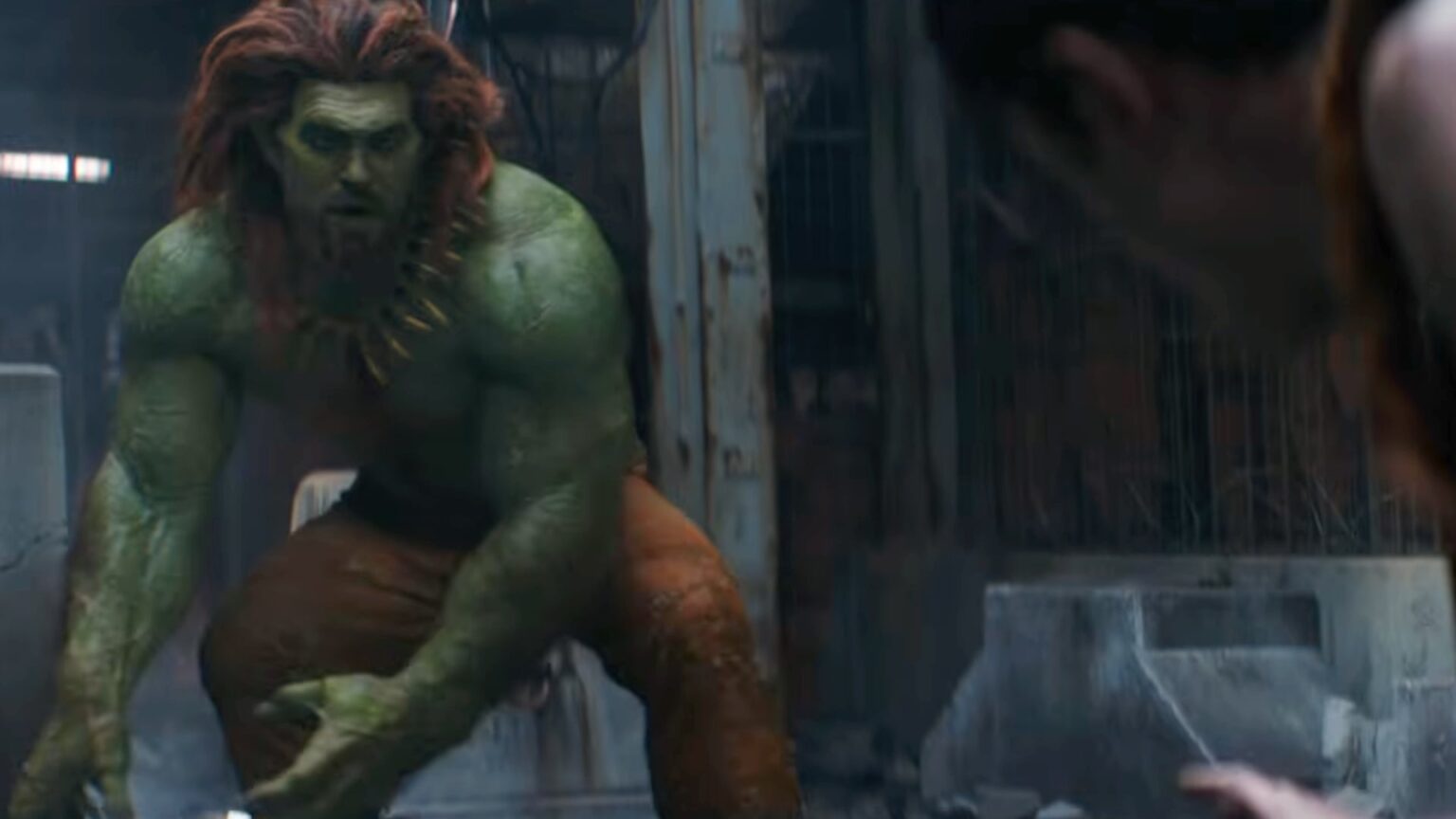 Jason Momoa caracterizado como Blanka de Street Fighter con piel verde, cabello naranja y postura agachada.