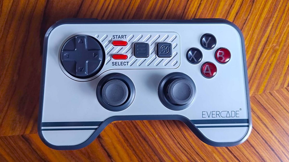 Mando de videojuegos Evercade gris con dos joysticks, cruceta y botones ABXY sobre una mesa de madera.