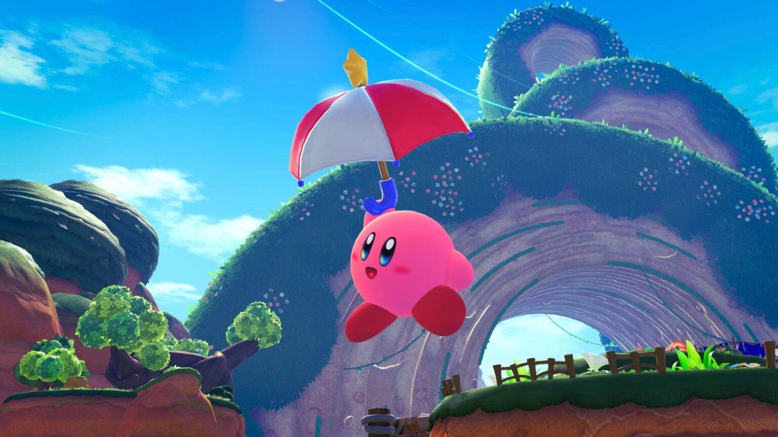 Kirby flota en el aire con un paraguas rojo y blanco en un paisaje verde.